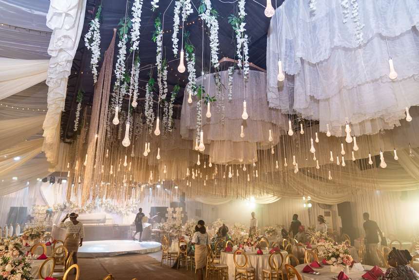Round banquet tables dressed in white with wine napkins and gold chairs.