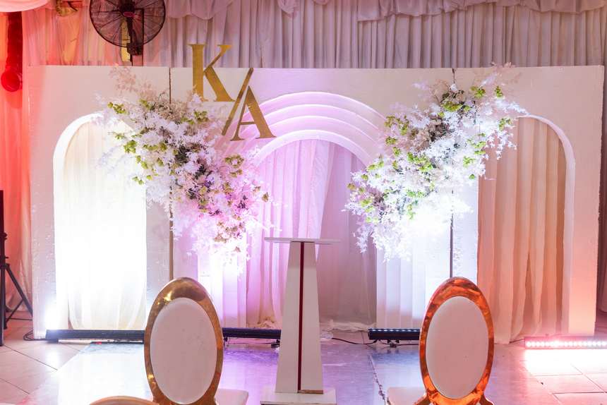 An arched backdrop with monogram lettering and florals, lit from below.